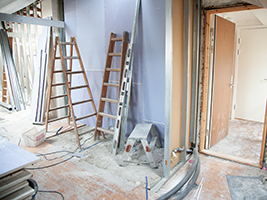 picture of a room that is being renovated with a ladder in view and bare walls of drywall